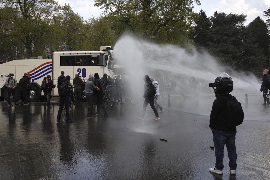 Police use tear gas and a water cannon to disperse gatherers at the Bois de la Cambre park during a party called "La Boum 2" in Brussels, Saturday, May 1, 2021. Police put on extra patrols Saturday to monitor the gathering which is being held in defiance of Belgium's current COVID-19 regulations. (AP Photo/Olivier Matthys)