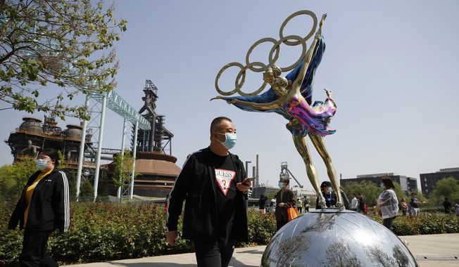 Visitors wearing face masks to help curb the spread of the coronavirus walk by a statue featuring Winter Olympics figure skating on display at the Shougang Park in Beijing, Sunday, May 2, 2021. (AP Photo/Andy Wong) ** FILE **