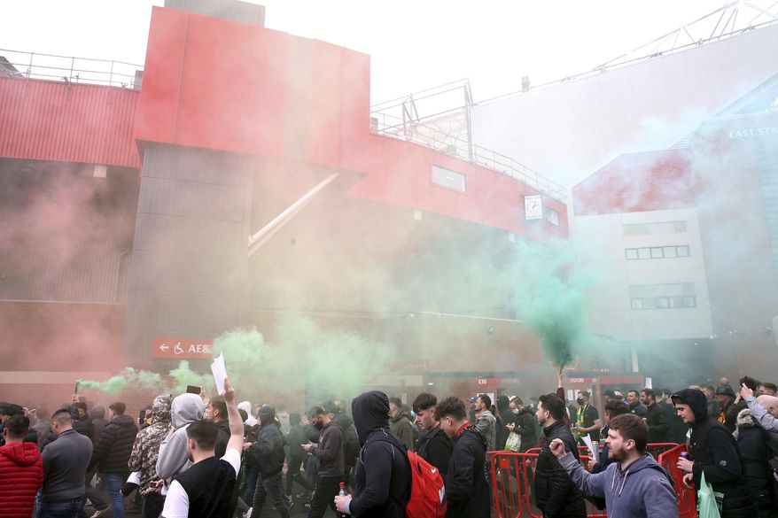 Fans make their way past barriers outside the ground as they let off flares whilst protesting against the Glazer family, owners of Manchester United, before their Premier League match against Liverpool at Old Trafford, Manchester, England, Sunday, May 2, 2021. (Barrington Coombs/PA via AP)