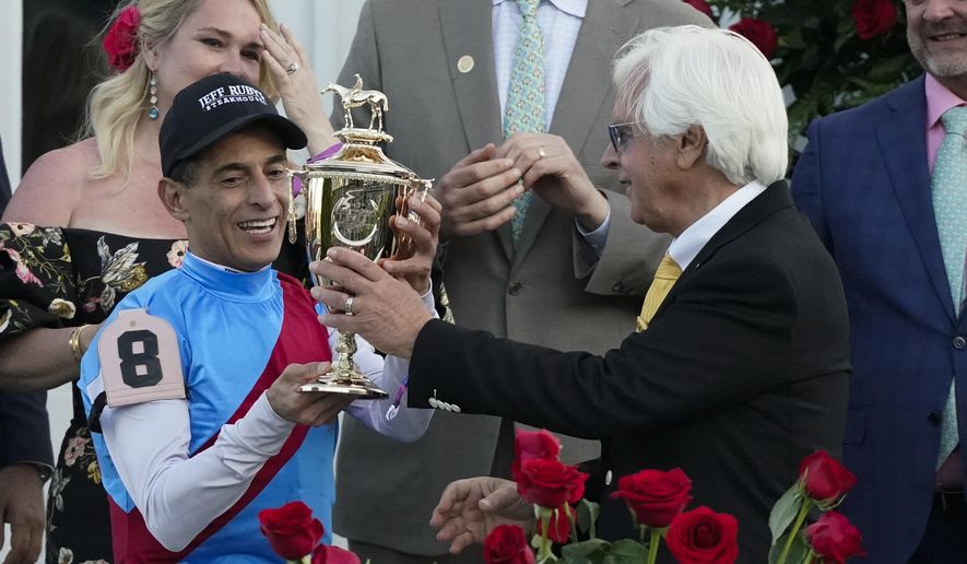Trainer Bob Baffert hands the winner&#39;s trophy to jockey John Velazquez after they victory with Medina Spirit in the 147th running of the Kentucky Derby at Churchill Downs, Saturday, May 1, 2021, in Louisville, Ky. (AP Photo/Jeff Roberson) **FILE**