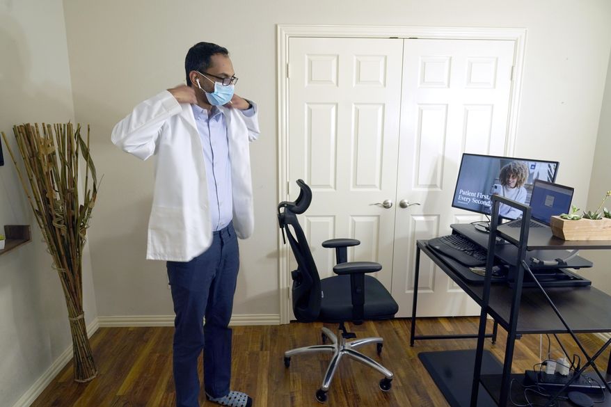 Medical director of Doctor on Demand Dr. Vibin Roy prepares to conduct an online visit with a patient from his work station at home, Friday, April 23, 2021, in Keller, Texas. Some U.S. employers and insurers want you to make telemedicine your first choice for most doctor visits. Retail giant Amazon and several insurers have started or expanded virtual-first care plans to get people thinking telemedicine routinely, even for annual checkups. (AP Photo/LM Otero)