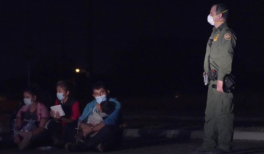 In this March 24, 2021 photo, a migrant man, center, holds a child as he looks at a U.S. Customs and Border Protection agent at an intake area after crossing the U.S.-Mexico border, early Wednesday, March 24, 2021, in Roma, Texas. The Biden administration said Monday that four families that were separated at the Mexico border during Donald Trump&#39;s presidency will be reunited in the United States this week in what Homeland Security Secretary Alejandro Mayorkas calls “just the beginning” of a broader effort. (AP Photo/Julio Cortez)