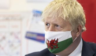 Britain&#39;s Prime Minister Boris Johnson wears a Welsh flag face mask during a visit to Barry Island, Wales, as part of the Welsh Conservative Party&#39;s Senedd election campaign, Monday, May 3, 2021. (Matthew Horwood/PA via AP)