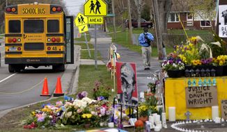 A school bus driver stops to look at a makeshift memorial at the site where Daunte Wright was killed a day after he was laid to rest, Friday, April 23, 2021, in Brooklyn Center, Minn. The 20-year-old Wright was killed by then-Brooklyn Center police officer Kim Potter during a traffic stop. (AP Photo/Julio Cortez)