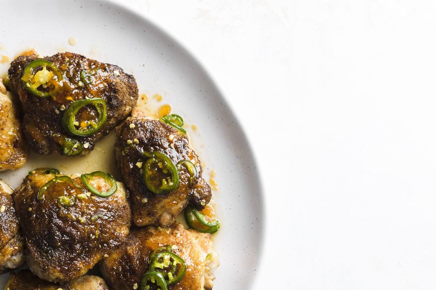 This image released by Milk Street shows a recipe for glazed chicken thighs, seasoned with jalapenos and apricot preserves. A dusting of earthy cumin on the chicken before roasting helps ground the flavors and balance the brighter sweetness of the preserves. (Milk Street via AP)
