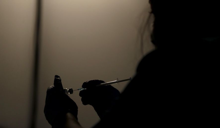 A volunteer vaccinator prepares to administer a dose of the Pfizer coronavirus vaccine at a vaccine centre in the Swaminarayan School in Neasden, north London, Saturday, May 1, 2021. (AP Photo/Matt Dunham)