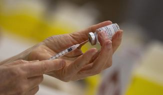 In this file photo dated Wednesday, April 14, 2021, a pharmacist fills a syringe from a vial of the Moderna COVID-19 vaccine in Antwerp, Belgium. (AP Photo/Virginia Mayo, File)