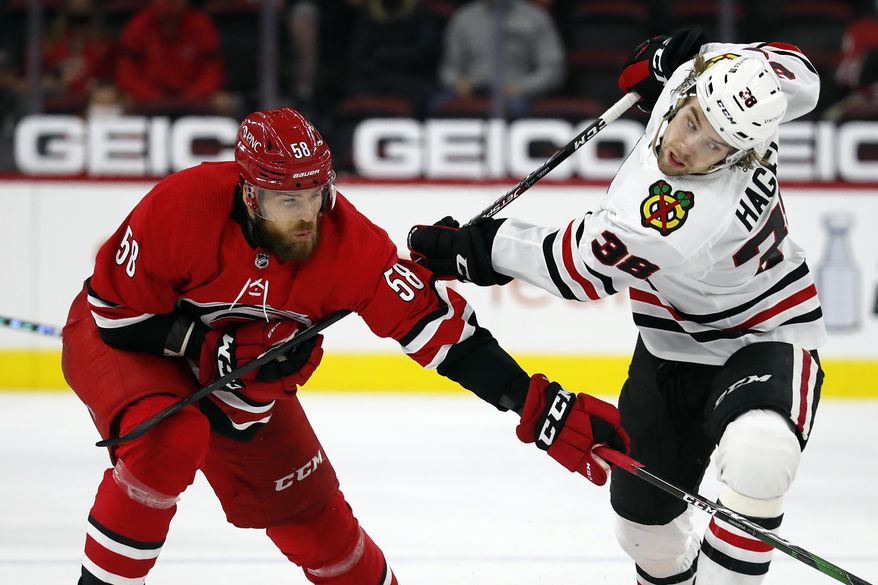 Chicago Blackhawks' Brandon Hagel (38) tangles with Carolina Hurricanes' Jani Hakanpaa (58) during the second period of an NHL hockey game in Raleigh, N.C., Tuesday, May 4, 2021. (AP Photo/Karl B DeBlaker)