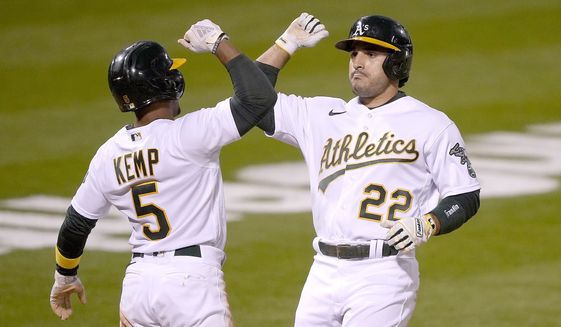 Oakland Athletics&#39; Ramon Laureano (22) gets a forearm-bash with his teammates Tony Kemp (5) after hitting a two-run home run against the Toronto Blue Jays during the fifth inning of a baseball game in Oakland, Calif., on Monday, May 3, 2021. (AP Photo/Tony Avelar)
