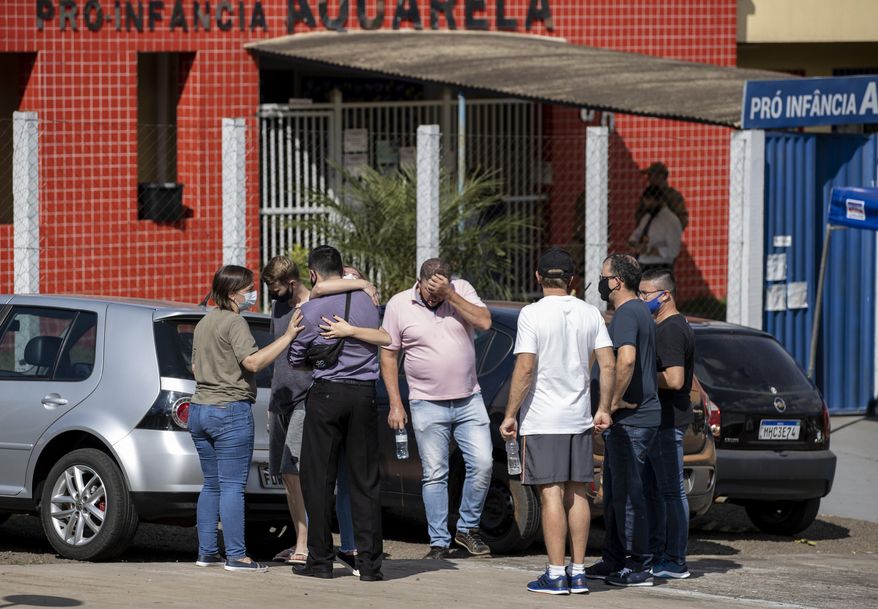 Relatives gather outside the Aquarela preschool in Saudades, in the southern state of Santa Catarina, Brazil, Tuesday, May 4, 2021. According to police an 18-year-old teenager entered the day care center with a knife and stabbed and killed three children and a teacher. (AP Photo/Liamara Polli)