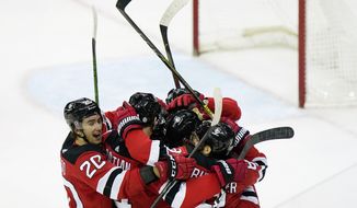 New Jersey Devils center Michael McLeod (20) surrounds teammates, including New Jersey Devils center Pavel Zacha (37), center, (seen only by his helmet) after Zacha scored a game-winning goal in playoff-bound Boston Bruins, Tuesday, May 4, 2021, in Newark, N.J. (AP Photo/Kathy Willens)