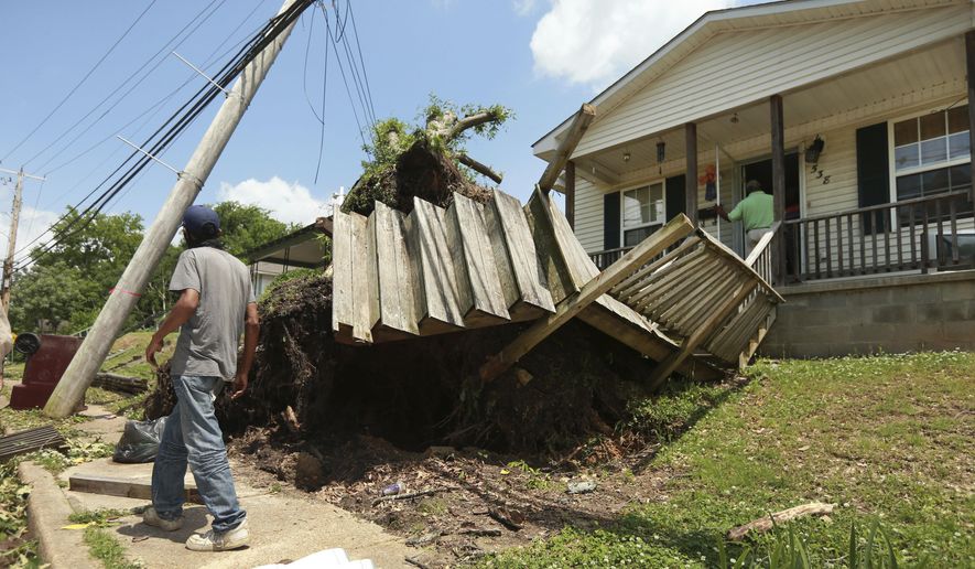 A Tupelo resident walks by a home on North Green Street on Monday, May 3, 2021 that had a tree fall and it roots tear out the decking and stairway to the home after a tornado passed through the city Sunday night. (Adam Robison/The Northeast Mississippi Daily Journal via AP)