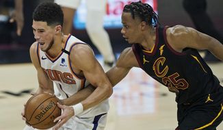 Phoenix Suns&#39; Devin Booker, left, drives past Cleveland Cavaliers&#39; Isaac Okoro in the first half of an NBA basketball game, Tuesday, May 4, 2021, in Cleveland. (AP Photo/Tony Dejak)