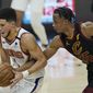Phoenix Suns&#x27; Devin Booker, left, drives past Cleveland Cavaliers&#x27; Isaac Okoro in the first half of an NBA basketball game, Tuesday, May 4, 2021, in Cleveland. (AP Photo/Tony Dejak)