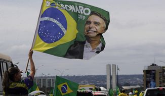 A demonstrator waves a banner with an image of President Jair Bolsonaro, during a caravan backing Bolsonaro’s anti-coronavirus-lockdown stance, marking May Day, or International Workers&#39; Day, in Brasilia, Brazil, Saturday, May 1, 2021. (AP Photo/Eraldo Peres)