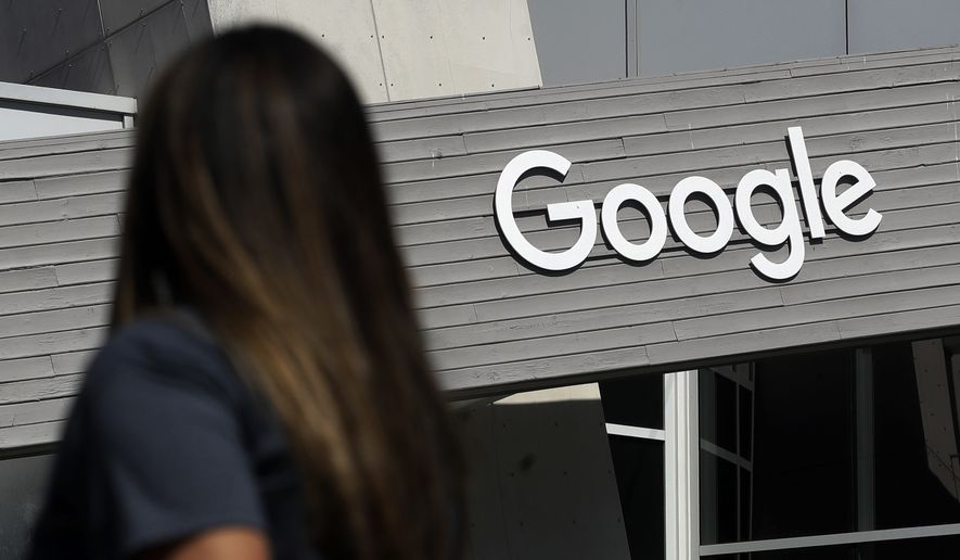 In this Sept. 24, 2019, file photo, a woman walks below a Google sign on the campus in Mountain View, Calif. On Wednesday, May 5, 2021, Google said that it expects about 20% of its workforce to still work remotely after the coronavirus pandemic. In addition, some 60% will work a hybrid schedule that includes about three days in the office and two days wherever the employees work best. (AP Photo/Jeff Chiu, File)