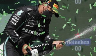 Mercedes driver Lewis Hamilton of Britain celebrates on the podium after winning the Portugal Formula One Grand Prix at the Algarve International Circuit near Portimao, Portugal, Sunday, May 2, 2021. (AP Photo/Manu Fernandez)
