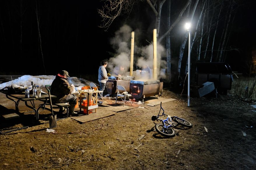 The Maday family boils maple sap into syrup on March 19, 2021, in their front yard on the Bad River Band of Lake Superior Chippewa reservation in Wisconsin. As with most Ojibwe traditional ways, tapping trees in the early spring and gathering sap for syrup and sugar cakes not only provides tasty food but offers lessons for life. (Mary Annette Pember/Indian Country Today via AP)