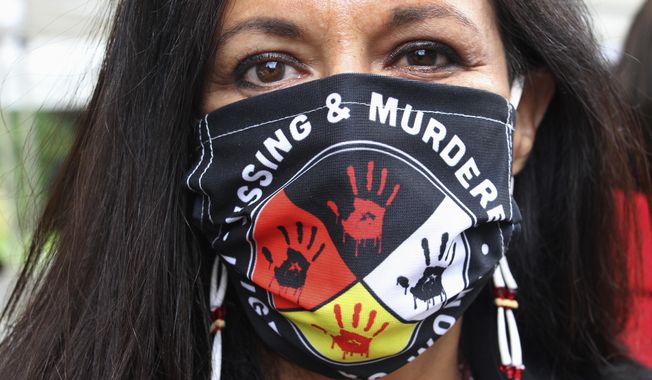FILE - In this Wednesday, Aug. 26, 2020, file photo, Jeannie Hovland, the deputy assistant secretary for Native American Affairs for the U.S. Department of Health and Human Services, poses with a Missing and Murdered Indigenous Women mask, in Anchorage, Alaska, while attending the opening of a Lady Justice Task Force cold case office in Anchorage, which will investigate missing and murdered Indigenous women. From the nation’s capitol to Indigenous communities across the American Southwest, top government officials, family members and advocates are gathering Wednesday, May 5, 2021, as part of a call to action to address the ongoing problem of violence against Indigenous women and children. (AP Photo/Mark Thiessen, File)