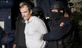 FILE - In this June 15, 2016 file photo provided by the Mexican Attorney General&#39;s Office, Hector &amp;quot;El Guero&amp;quot; Palma, or “Blondie,” one of the founders of the Sinaloa Cartel, is escorted in handcuffs from a helicopter at a federal hangar in Mexico City, after serving almost a decade in a U.S. prison and transported to another maximum-security lockup to await trial for two murders. (Mexico&#39;s Attorney General&#39;s Office via AP, File)