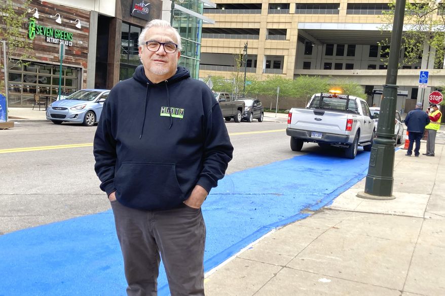 Tony Sacco, co-owner of Mootz Pizzeria and Bar in Detroit, stands on Library Street near his restaurant Wednesday, May 5, 2021. Sacco painted a portion of the street blue to clear up confusion about parking in a handicap zone that only has a single handicap sign. Sacco said it's confusing because parking enforcers consider the space reserved for as many as four vehicles. A city traffic engineer told Sacco that more signs will be installed but the blue paint will be removed. (AP Photo/Ed White)