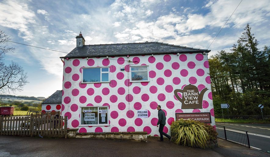 A man walks past a polling station in the Bank View Cafe in Sheffield, England as polls open for local, mayoral, Welsh and Scottish Government elections, Thursday May 6, 2021. Millions of people across Britain will cast a ballot on Thursday, in local elections, the biggest set of votes since the 2019 general election. A Westminster special-election is also taking place in Hartlepool, England. (Danny Lawson/PA via AP)