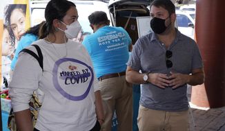 Rep. Ruben Gallego, D-Ariz., right, is joined by Kristin Urquiza, left, speak at a pop-up informational tent increasing efforts to bring more vaccine doses into Latino neighborhoods at a local shopping plaza Friday, May 7, 2021, in Phoenix. Gallego said he is helping organize vaccination events in Latino neighborhoods, including one May 15 at a west Phoenix high school. (AP Photo/Ross D. Franklin)