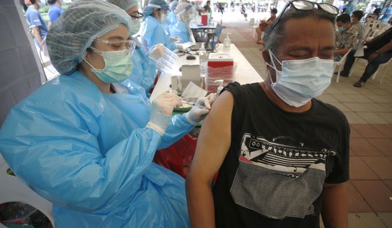 FILE - In this Tuesday, May 4, 2021, file photo, a health worker administers a dose of the Sinovac COVID-19 vaccine to residents of the Klong Toey area, a neighborhood currently having a spike in coronavirus cases, in Bangkok, Thailand. Thailand sought Thursday, May 6, 2021, to assure its foreign residents that they can get COVID-19 vaccinations, countering comments by some officials suggesting they would be at the end of the line for inoculations. (AP Photo/Anuthep Cheysakron)