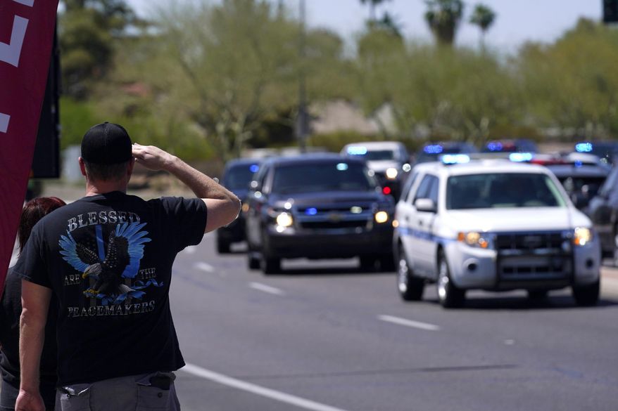 People line the streets as the body of Chandler Police Officer Christopher Farrar, killed in the line of duty last Thursday, is escorted during a large multi-jurisdiction police procession Friday, May 7, 2021, in Chandler, Ariz. Officer Farrar was struck by a suspect in a stolen vehicle after a long police chase. (AP Photo/Ross D. Franklin)