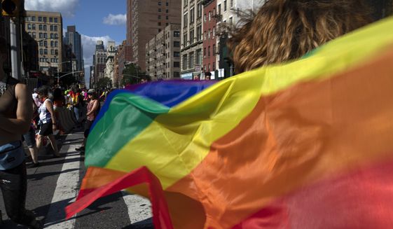 In this June 30, 2019, photo, parade-goers carrying rainbow flags walk down a street during the LBGTQ Pride march in New York, to celebrate five decades of LGBTQ pride, marking the 50th anniversary of the police raid that sparked the modern-day gay rights movement. (AP Photo/Wong Maye-E) **FILE**
