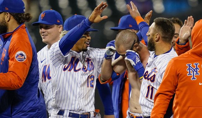 New York Mets&#x27; Francisco Lindor (12) celebrates with Patrick Mazeika, center right, who had his jersey removed by his teammates as they celebrate after Pete Alonso scored the winning run against the Arizona Diamondbacks on a grounder by Mazeika in the 10th inning of a baseball game Friday, May 7, 2021, in New York. (AP Photo/John Minchillo)