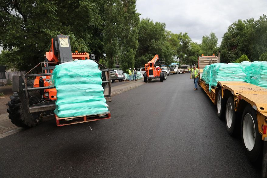 Sandbags are unloaded onto Main Street in the Sunnyside section of Flagstaff, Ariz. in 2019 as crews work to protect individual homes from potential floodwaters in the Museum Fire burn area. It's nearly two years since a fire burned nearly 2,000 acres in hills north of Flagstaff but rows of concrete barriers and stacks of sandbags remain in place in neighborhoods along a wash that runs down into the city. (Jake Bacon/Arizona Daily Sun via AP)