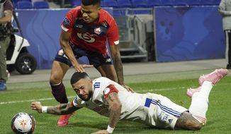 Lyon&#39;s Memphis Depay, down, challenges for the ball with Lille&#39;s Reinildo Isnard Mandava, up, during their French League One soccer match in Decines, near Lyon, central France, Sunday, April 25, 2021. (AP Photo/Laurent Cipriani)