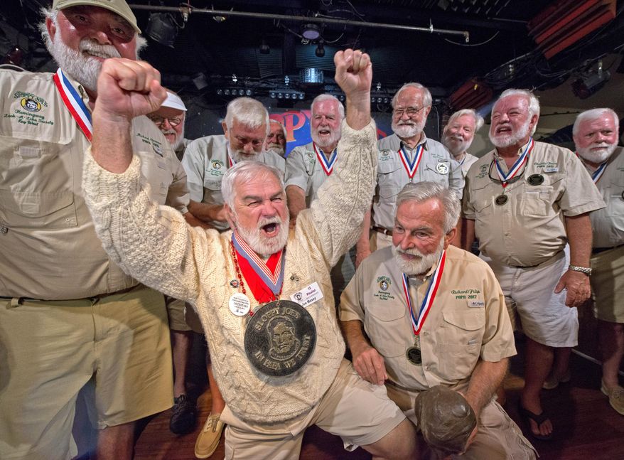 FILE - In this Saturday, July 20, 2019, file photo provided by the Florida Keys News Bureau, Joe Maxey, second from left, celebrates his victory at the Hemingway Look-Alike Contest at Sloppy Joe's Bar in Key West, Fla. After taking a year off due to the COVID-19 pandemic, organizers of the look-alike contest announced Friday, May 7, 2021, that the 2021 contest, the 40th edition, is planned for July 22-24. The competition is the cornerstone event of the Hemingway Days festival that salutes author Ernest Hemingway's July 21 birthday and 1930s residence in Key West. (Andy Newman/Florida Keys News Bureau via AP)