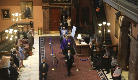 South Carolina senators walk across the Statehouse lobby for a joint session with the House on Wednesday, May 5, 2021, in Columbia, S.C. Senators sat in the balcony for the joint session because of COVID-19 concerns. (AP Photo/Jeffrey Collins)