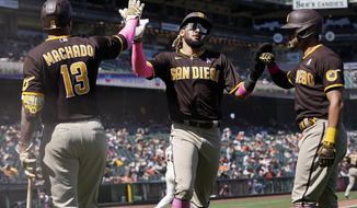 San Diego Padres&#39; Fernando Tatis Jr., middle, and Tommy Pham, right, are congratulated by Manny Machado (13) after both scored on a two-run triple hit by Trent Grisham during the eighth inning of a baseball game against the San Francisco Giants in San Francisco, Sunday, May 9, 2021. (AP Photo/Jeff Chiu)