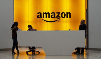 FILE - In this Feb. 14, 2019, file photo, people stand in the lobby for Amazon offices in New York. Amazon, which has been under pressure from shoppers, brands and lawmakers to crack down on counterfeits on its site, said Monday, May 10, 2021, that it blocked more than 10 billion suspected phony listings last year before any of their offerings could be sold. (AP Photo/Mark Lennihan, File)