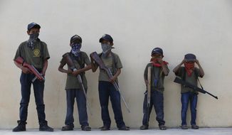 Children hold their training weapons, some real and some fake, during a display for the media designed to attract the federal government&#39;s attention to the dangers of organized crime their town negotiates daily in Ayahualtempa, Guerrero state, Mexico, Wednesday, April 28, 2021. International organizations have condemned the &amp;quot;recruitment&amp;quot; of children and warned of the effects. (AP Photo/Marco Ugarte)