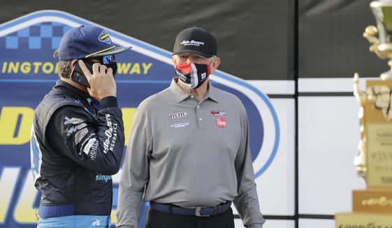 Martin Truex Jr. talks on a cell phone as team owner Joe Gibbs stands nearby after Truex won the NASCAR Cup Series auto race at Darlington Raceway, Sunday, May 9, 2021, in Darlington, S.C. (AP Photo/Terry Renna) **FILE**