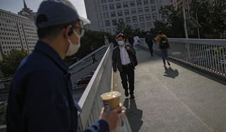 People wearing face masks to help curb the spread of the coronavirus walk on a pedestrian overhead bridge as they heading to work in Beijing, Monday, May 10, 2021. (AP Photo/Andy Wong)