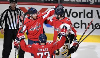 Washington Capitals left wing Michael Raffl (17) celebrates his goal with left wing Conor Sheary (73) and defenseman Justin Schultz (2) during the third period of an NHL hockey game as Boston Bruins center Cameron Hughes (53) skates away , Tuesday, May 11, 2021, in Washington. The Capitals won 2-1. (AP Photo/Nick Wass)