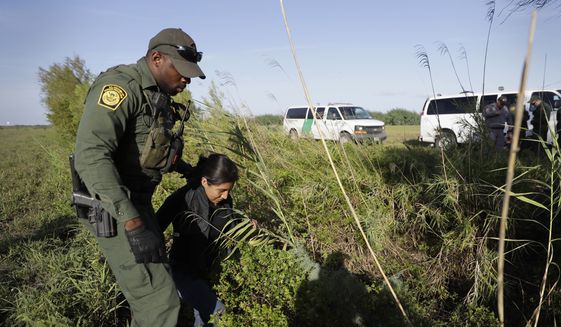In this Aug. 11, 2017, file photo, a U.S. Customs and Border Patrol agent escorts an immigrant suspected of crossing into the United States illegally along the Rio Grande near Granjeno, Texas. (AP Photo/Eric Gay, File)