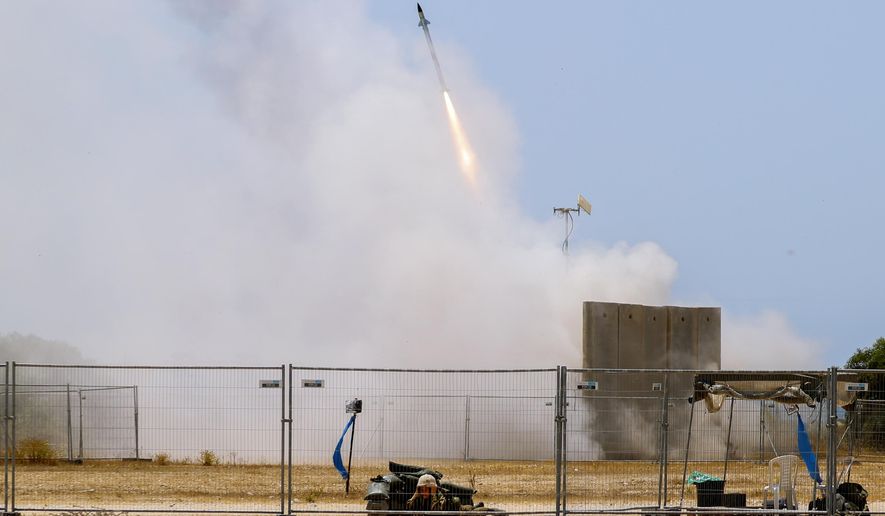 An Israeli soldier takes cover as an Iron Dome air defense system launches to intercept a rocket from the Gaza Strip, in Ashkelon, southern Israel, Tuesday, May 11, 2021. (AP Photo/Ariel Schalit) ** FILE **
