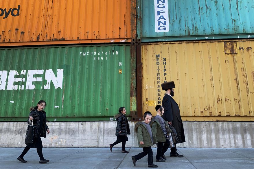 In this Tuesday, March 30, 2021 file photo, members of the Orthodox Jewish community walk past shipping containers in the South Williamsburg neighborhood of Brooklyn, New York. A comprehensive new survey of Jewish Americans finds them increasingly worried about antisemitism and sharply divided about the importance of religious observance in their lives. The wide-ranging survey, released on Tuesday, May 11, 2021, was conducted by the Pew Research Center. (AP Photo/Wong Maye-E)