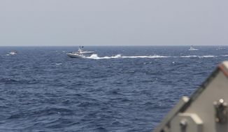In this image provided by the U.S. Navy, an Iranian Islamic Revolutionary Guard Corps Navy (IRGCN) fast in-shore attack craft (FIAC), a type of speedboat armed with machine guns, speeds near U.S. naval vessels transiting the Strait of Hormuz, Monday, May 10, 2021. U.S. officials say a group of 13 armed speedboats of Iran’s Revolutionary Guard made “unsafe and unprofessional” high-speed maneuvers toward U.S. Navy vessels in the Strait of Hormuz on Monday. A U.S. Coast Guard cutter fired warning shots when two of the Iranian boats came dangerously close. (U.S. Navy via AP)