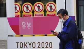 A man wearing a protective mask to help curb the spread of the coronavirus walks past a banner for the Tokyo 2020 Olympic and Paralympic Games in Tokyo Tuesday, May 11, 2021. The Japanese capital confirmed more than 920 new coronavirus cases on Tuesday. (AP Photo/Eugene Hoshiko)