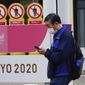 A man wearing a protective mask to help curb the spread of the coronavirus walks past a banner for the Tokyo 2020 Olympic and Paralympic Games in Tokyo Tuesday, May 11, 2021. The Japanese capital confirmed more than 920 new coronavirus cases on Tuesday. (AP Photo/Eugene Hoshiko)