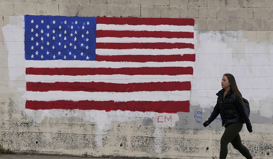 In this May 13, 2021, file photo, pedestrian walks in front of an American flag painted on a wall during the coronavirus outbreak in San Francisco. (AP Photo/Jeff Chiu, File)  **FILE**