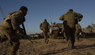 Israeli soldiers run for cover under armored vehicles as a siren sounds warning of incoming rockets fired from Gaza strip in a staging area near the Israeli-Gaza border southern Israel, Saturday, May 15, 2021. (AP Photo/Maya Alleruzzo)a