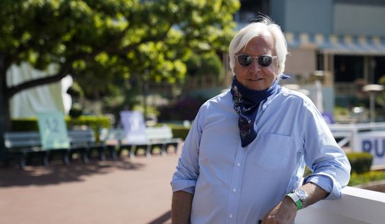 In this May 22, 2020, file photo, Bob Baffert, two-time Triple Crown-winning trainer, lowers his bandana during an interview while keeping his distance at Santa Anita Park in Arcadia, Calif. Baffert has been temporarily suspended from entering horses at New York racetracks pending an investigation into Kentucky Derby winner Medina Spirit. (AP Photo/Ashley Landis, File) **FILE**